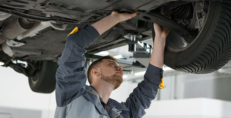 Handwerker arbeitet am Unterboden eines Autos