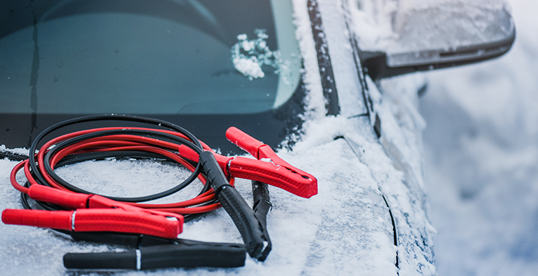 Auto steht im Schnee mit Überbrückungskabel