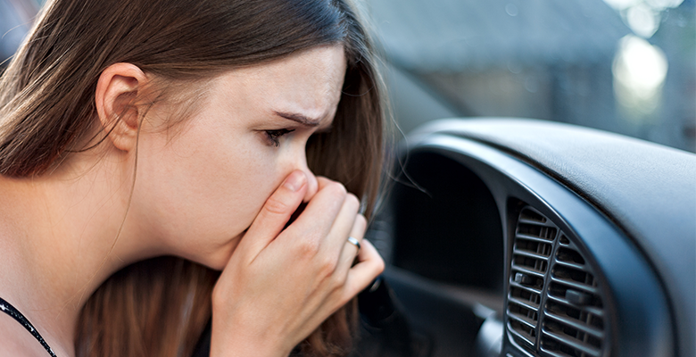 Frau hält sich vor der Klimaanlage im Auto die Nase zu - Was tun bei Geruch?