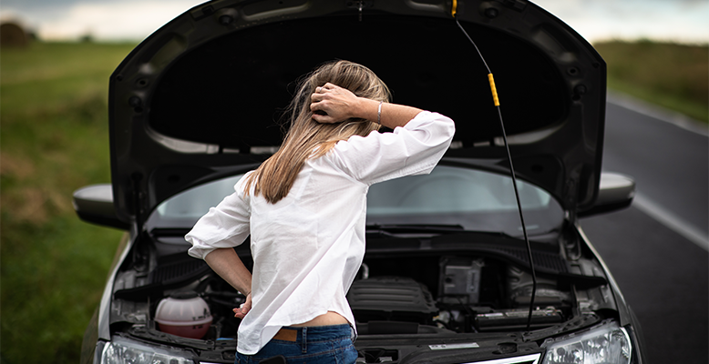 Frau steht vor offener Motorhaube