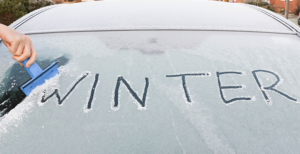 Auf einer zugefrorenen Autoscheibe steht "Winter"