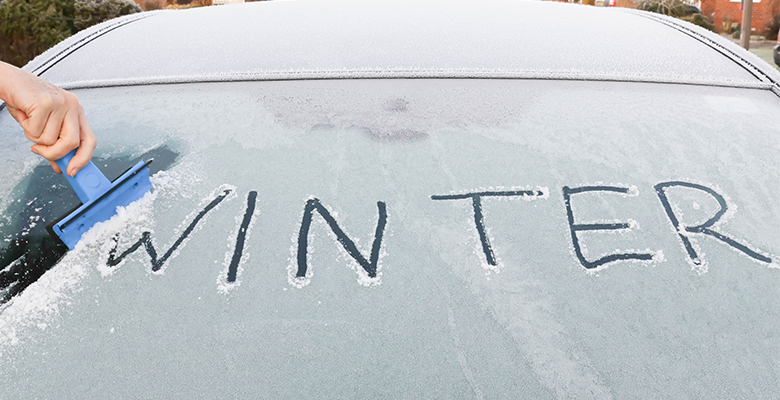 Wie kratze ich die Windschutzscheibe richtig? Auf einer zugefrorenen Autoscheibe steht "Winter"