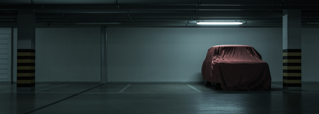 Roter überdachter Vintage-Wagen auf leerer Tiefgarage mit zwei Säulen.