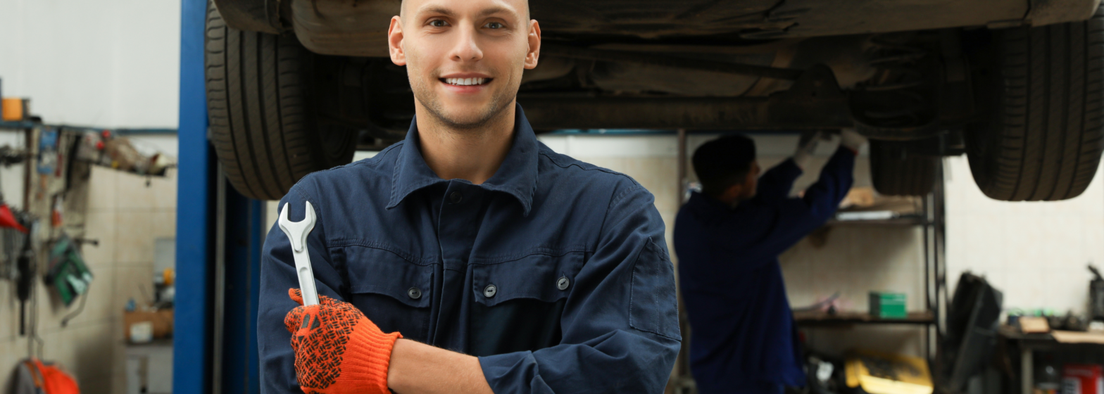 Porträt von professionellen Mechanikern mit Schraubschlüssel in der Kfz-Werkstatt.