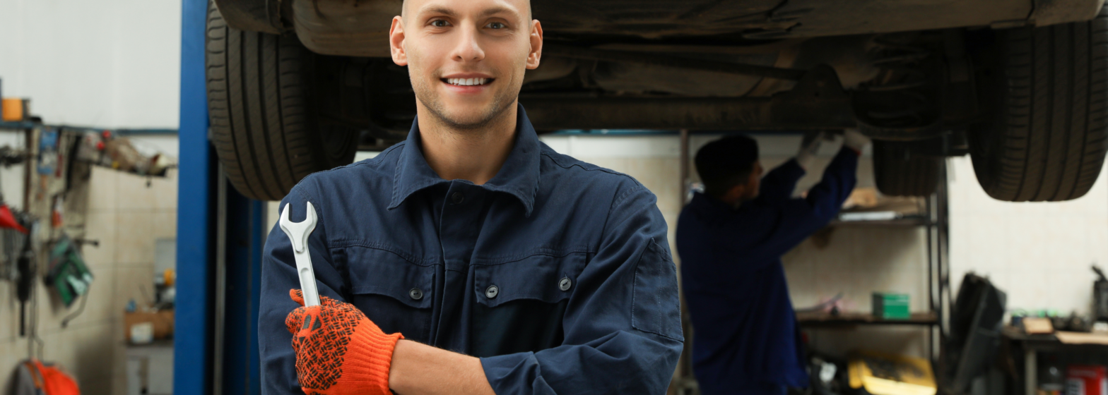 Portrait von professionellen Mechanikern mit Schraubschlüssel in der Kfz-Werkstatt.